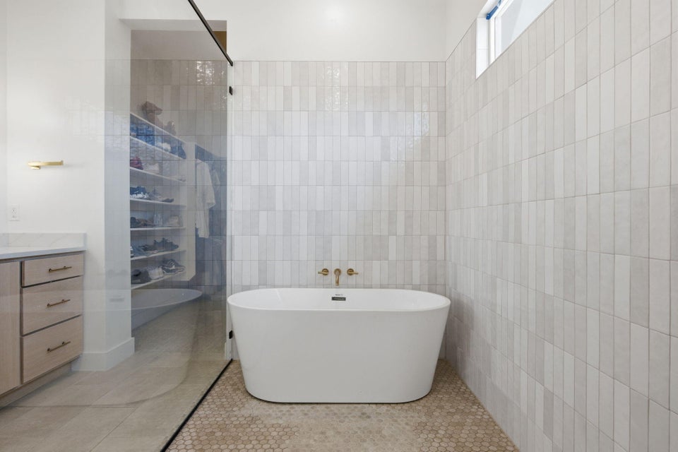 Bathroom featuring vanity, a freestanding bath, tile walls, light tile patterned floors, and a shower