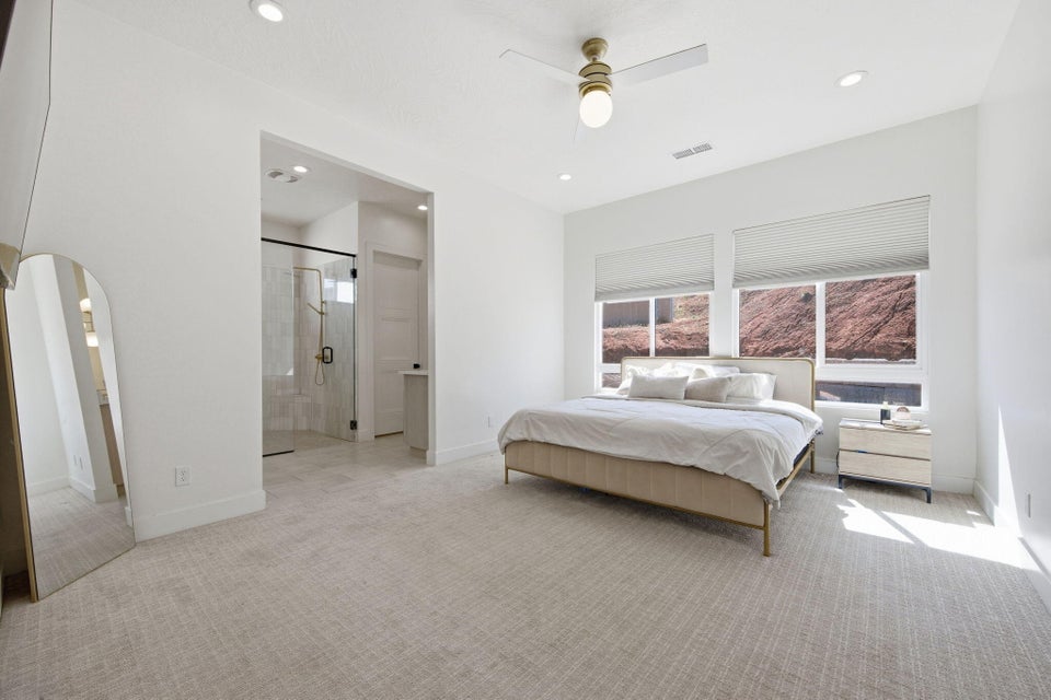 Bedroom featuring arched walkways, light carpet, a ceiling fan, ensuite bathroom, and recessed lighting