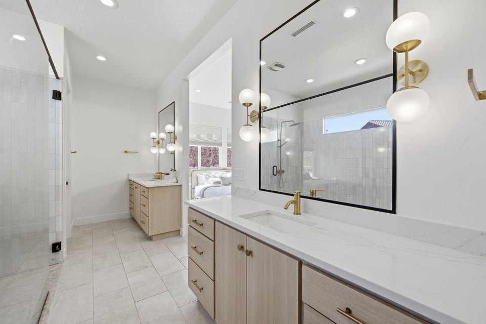 Bathroom featuring two vanities, a stall shower, light tile patterned floors, and recessed lighting