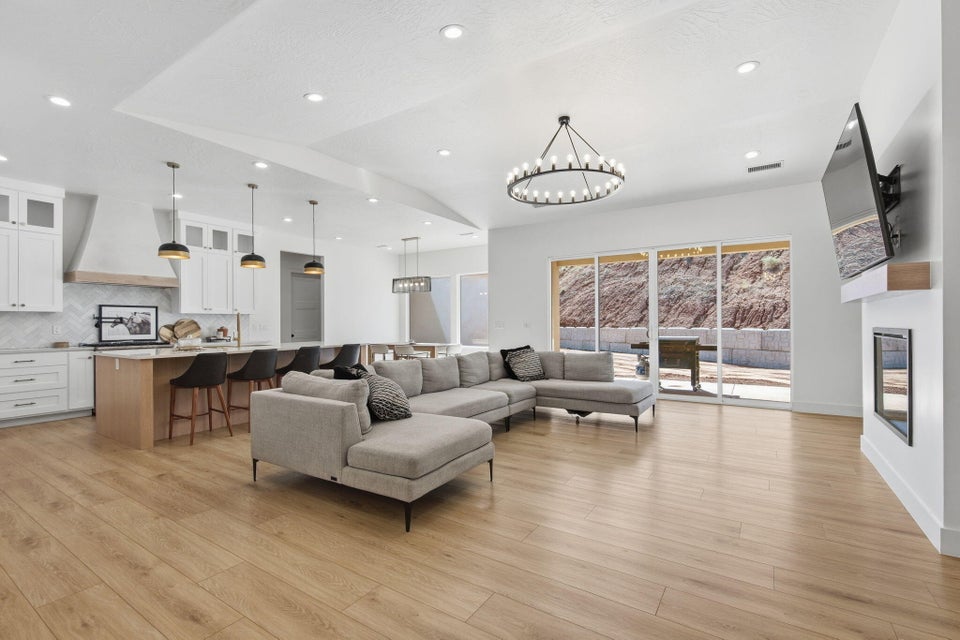 Living room featuring suspended lighting, light wood-style flooring, and a fireplace