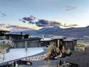 View of front of home featuring stone siding, a mountain view, an attached garage, concrete driveway, and board and batten siding