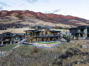 Back of property with a mountain view, a balcony, and a patio area