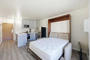Bedroom featuring freestanding refrigerator and light wood-style floors
