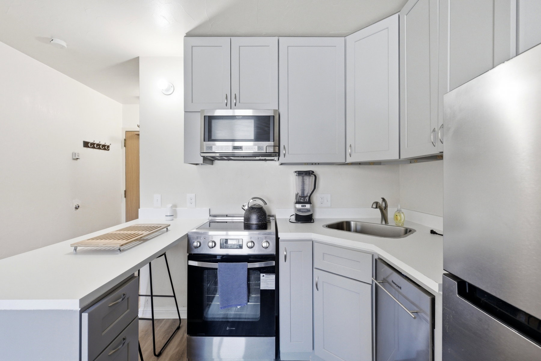 Kitchen featuring stainless steel appliances, gray cabinetry, and a peninsula