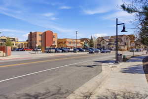 View of asphalt street with sidewalks, curbs, and street lighting