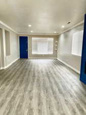 Unfurnished living room with light wood-type flooring, a textured ceiling, recessed lighting, and ornamental molding