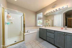 Bathroom with double vanity, light tile patterned floors, a stall shower, and a bath