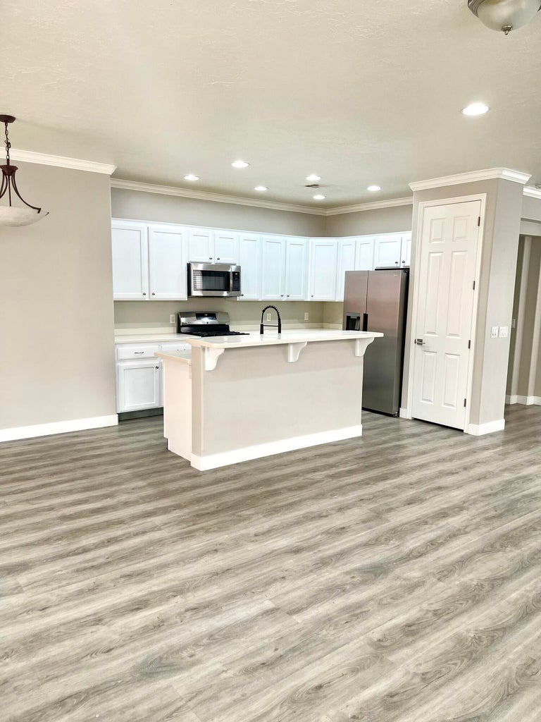 Kitchen with light countertops, white cabinetry, stainless steel appliances, a breakfast bar, and ornamental molding