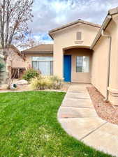 Property entrance with stucco siding and a yard