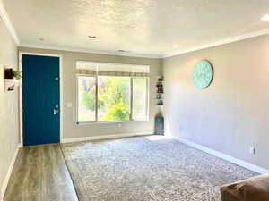 Entryway with a textured ceiling, light wood-style floors, crown molding, and recessed lighting