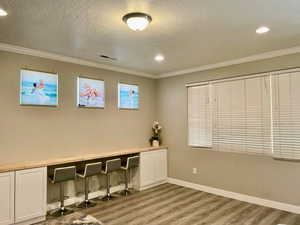 Office space with light wood-style floors, ornamental molding, a textured ceiling, and recessed lighting
