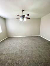 Unfurnished room with dark carpet, a ceiling fan, and a textured ceiling