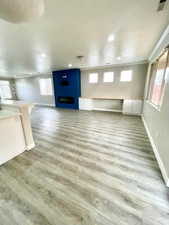 Unfurnished living room with light wood finished floors, recessed lighting, and a large fireplace