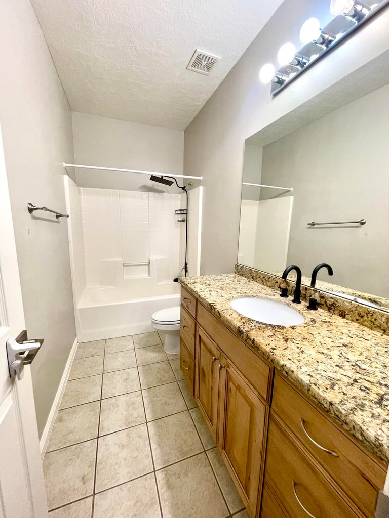 Bathroom with vanity, shower / bathtub combination, light tile patterned floors, and a textured ceiling