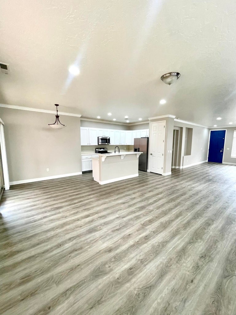 Unfurnished living room featuring light wood-style floors, crown molding, and recessed lighting