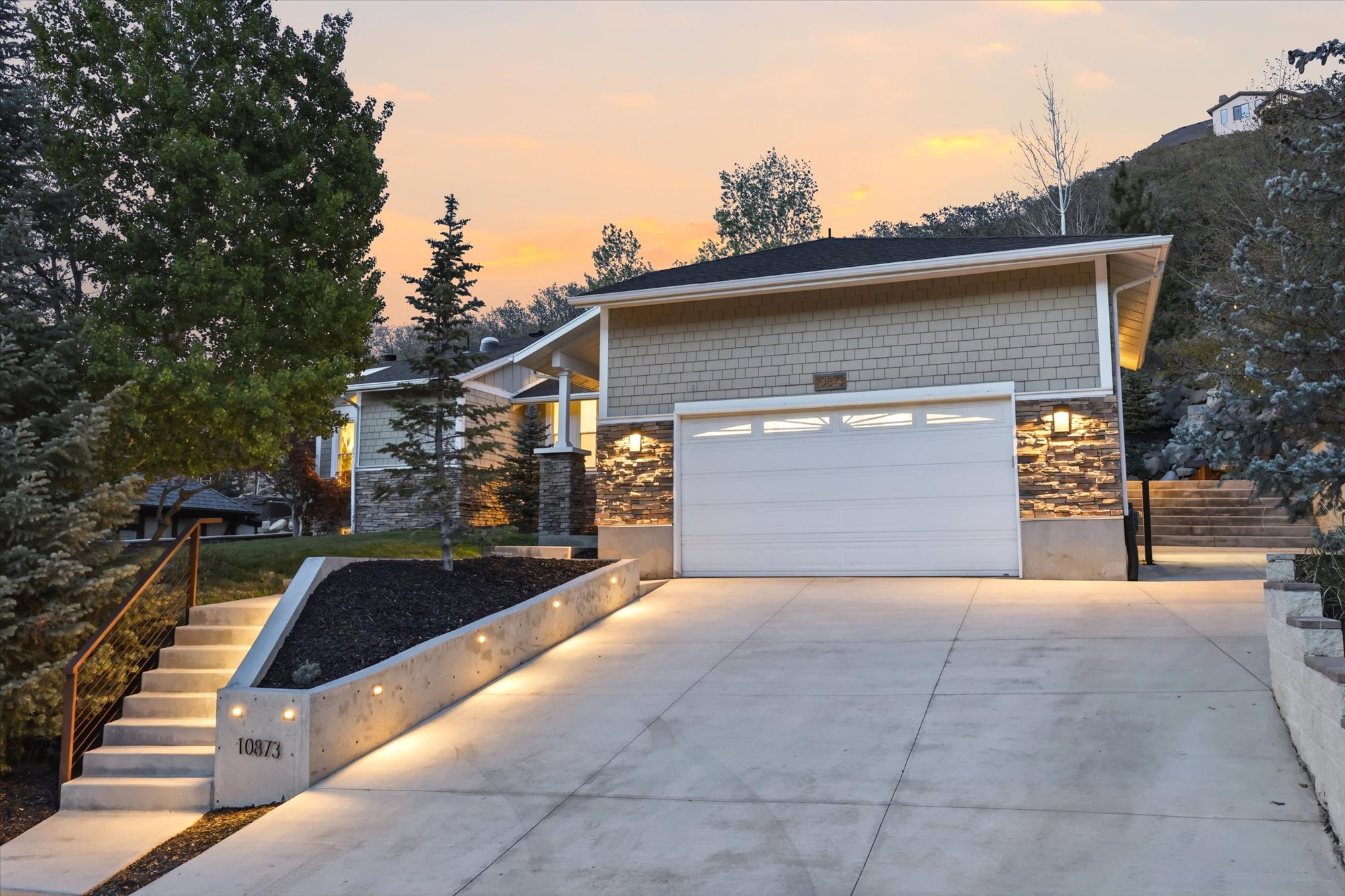 View of front of property with stone siding, concrete driveway, and an attached garage