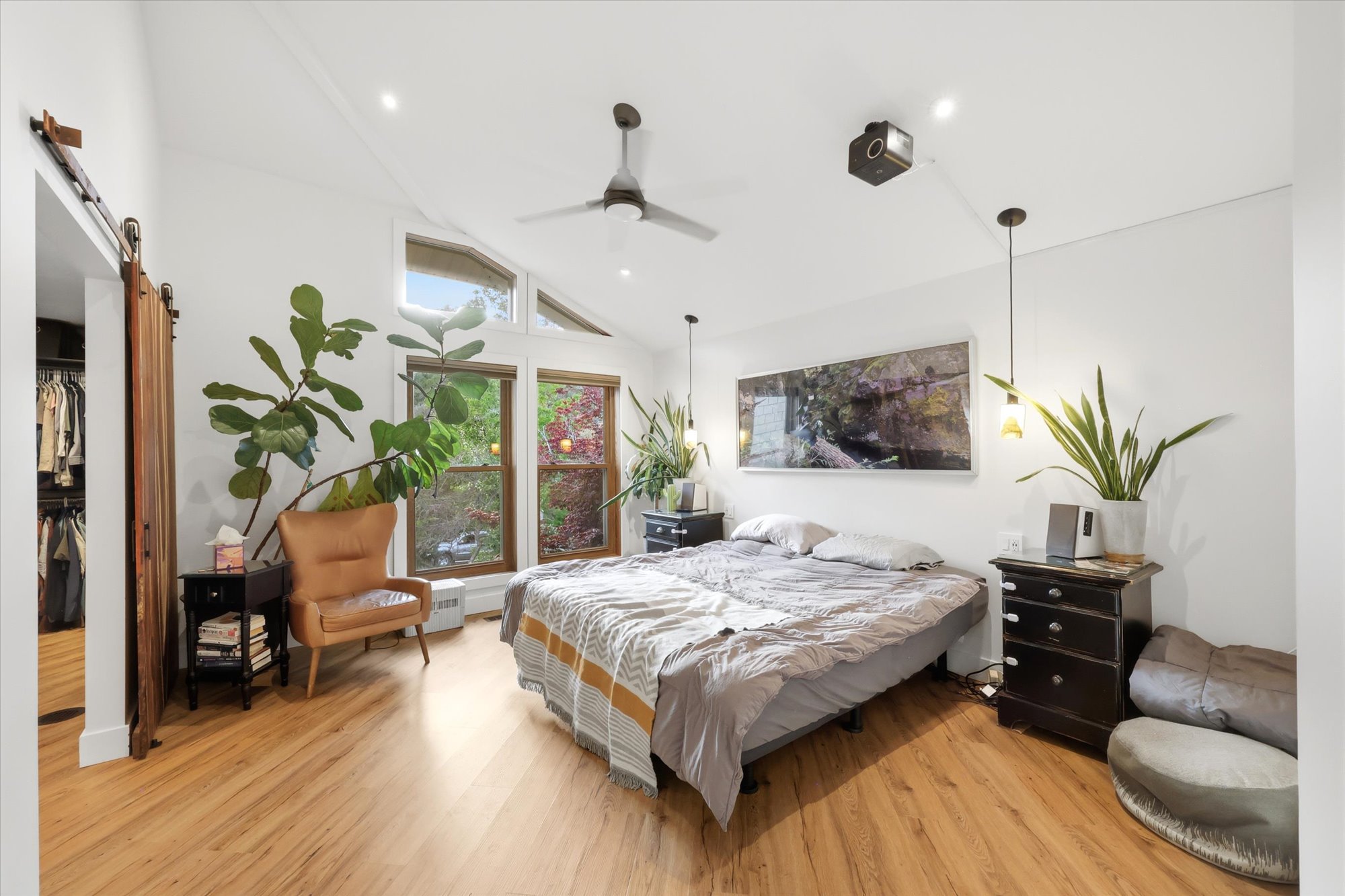Bedroom with a barn door, light wood-style floors, and lofted ceiling