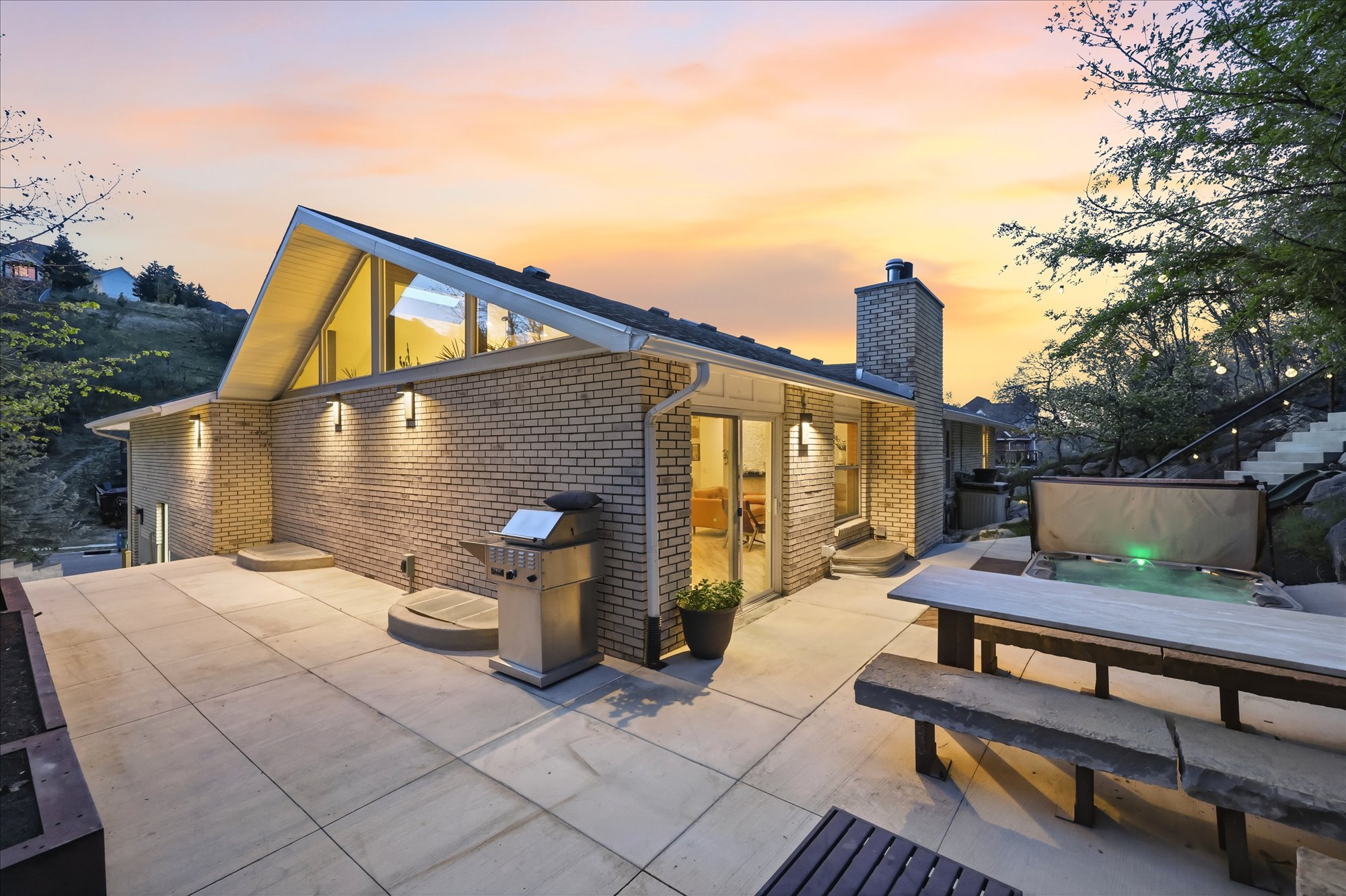 Back of house at dusk featuring brick siding, a chimney, and a patio
