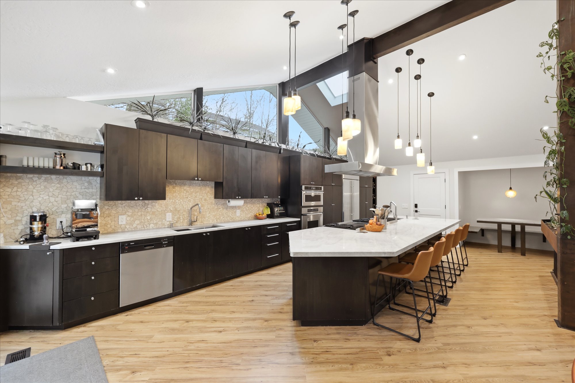 Kitchen featuring dark wood finish cabinetry, a large island, island range hood, a kitchen breakfast bar, and lofted ceiling