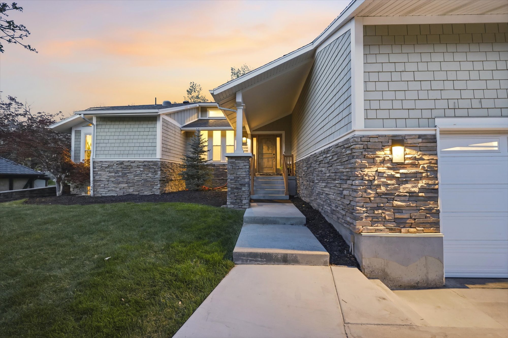 View of exterior entry with stone siding, a garage, and a yard