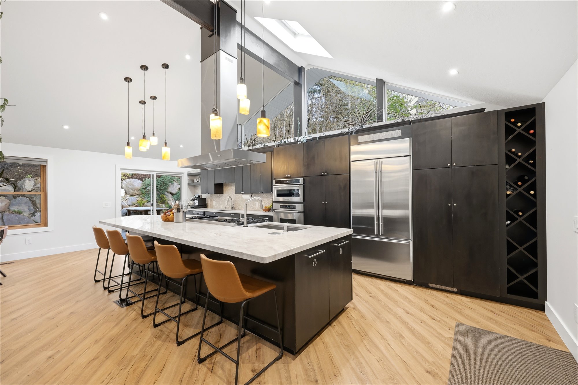 Kitchen with a kitchen bar, modern cabinets, a spacious island, dark wood finish cabinetry, and stainless steel appliances