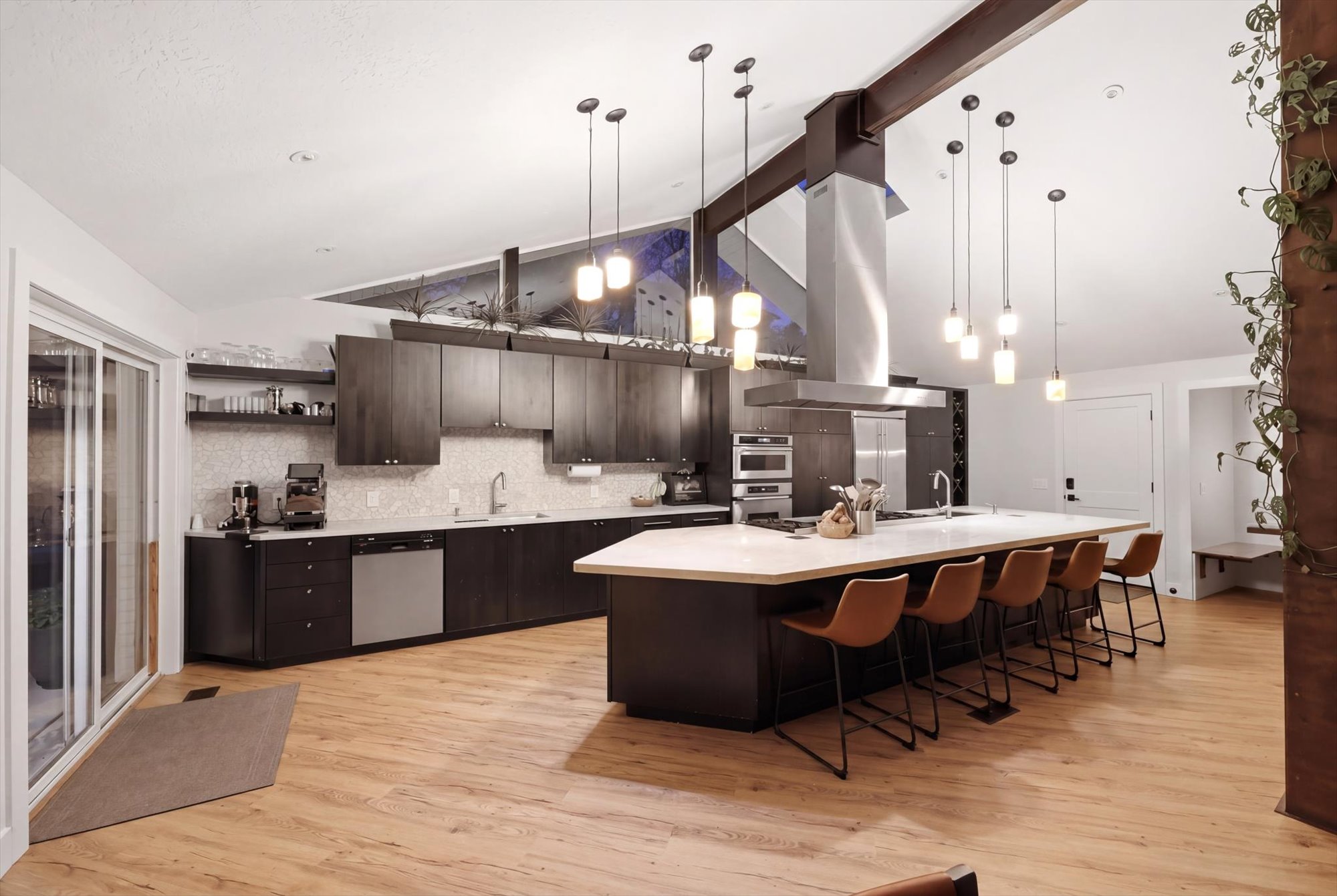 Kitchen with dark wood finish cabinetry, a kitchen bar, a spacious island, island exhaust hood, and stainless steel appliances