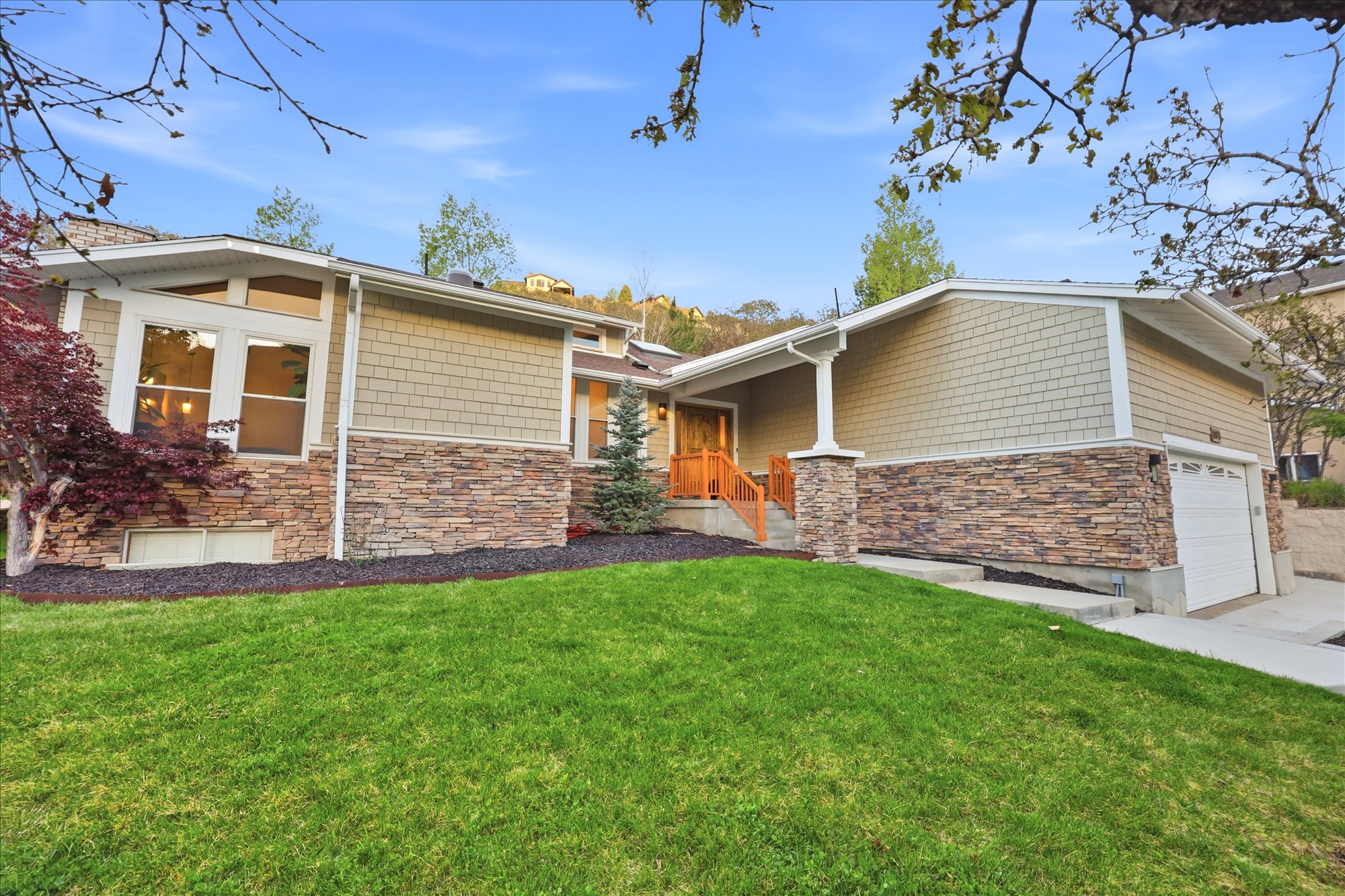 View of front of property featuring stone siding, a front yard, and driveway