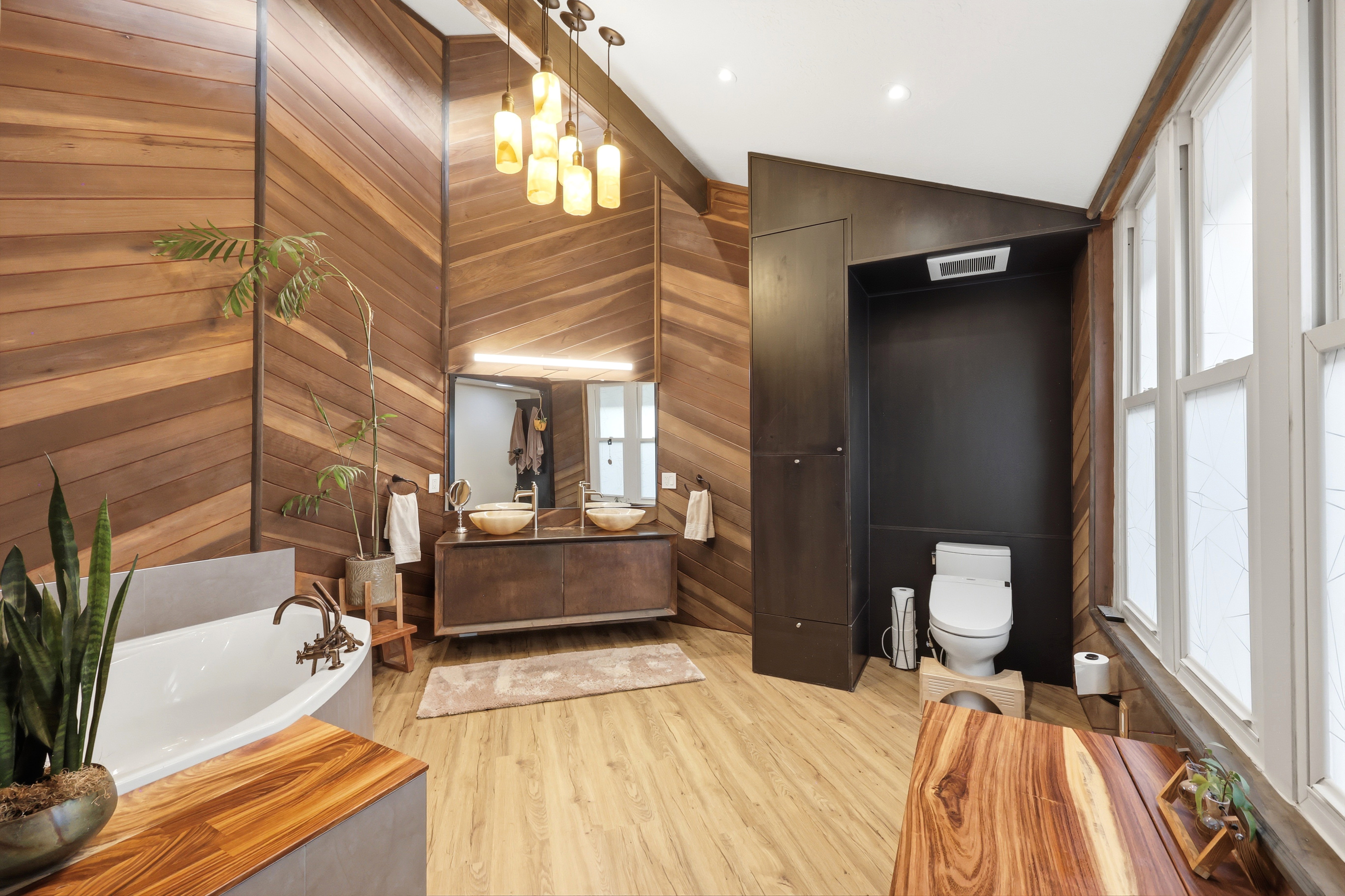 Full bathroom with double vanity, lofted ceiling, a garden tub, light wood-style flooring, and recessed lighting