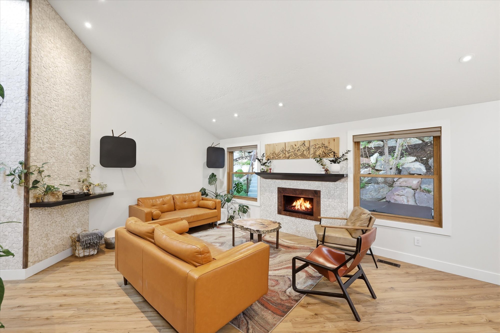 Living area with light wood finished floors, a lit fireplace, lofted ceiling, and recessed lighting