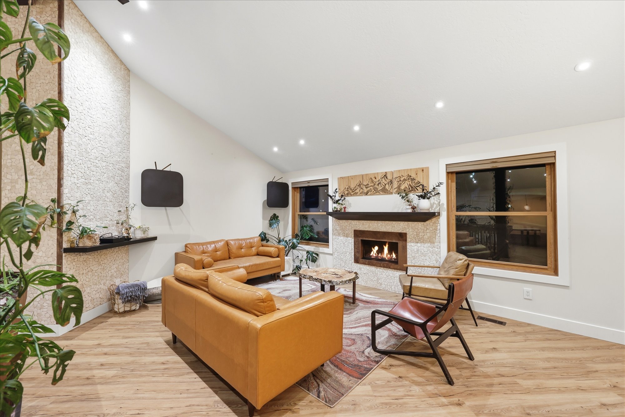 Living room featuring light wood finished floors, a warm lit fireplace, vaulted ceiling, and recessed lighting