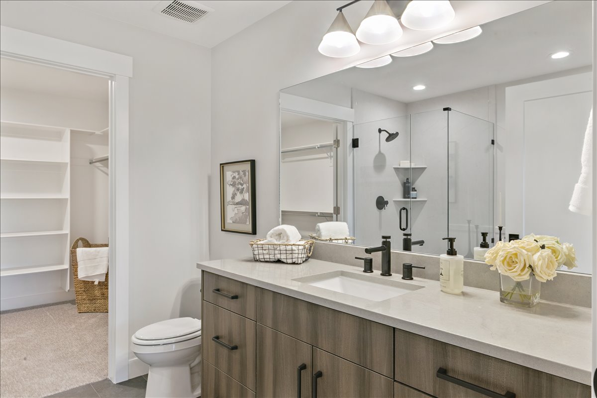 Bathroom with a walk in closet, a stall shower, vanity, light tile patterned floors, and recessed lighting