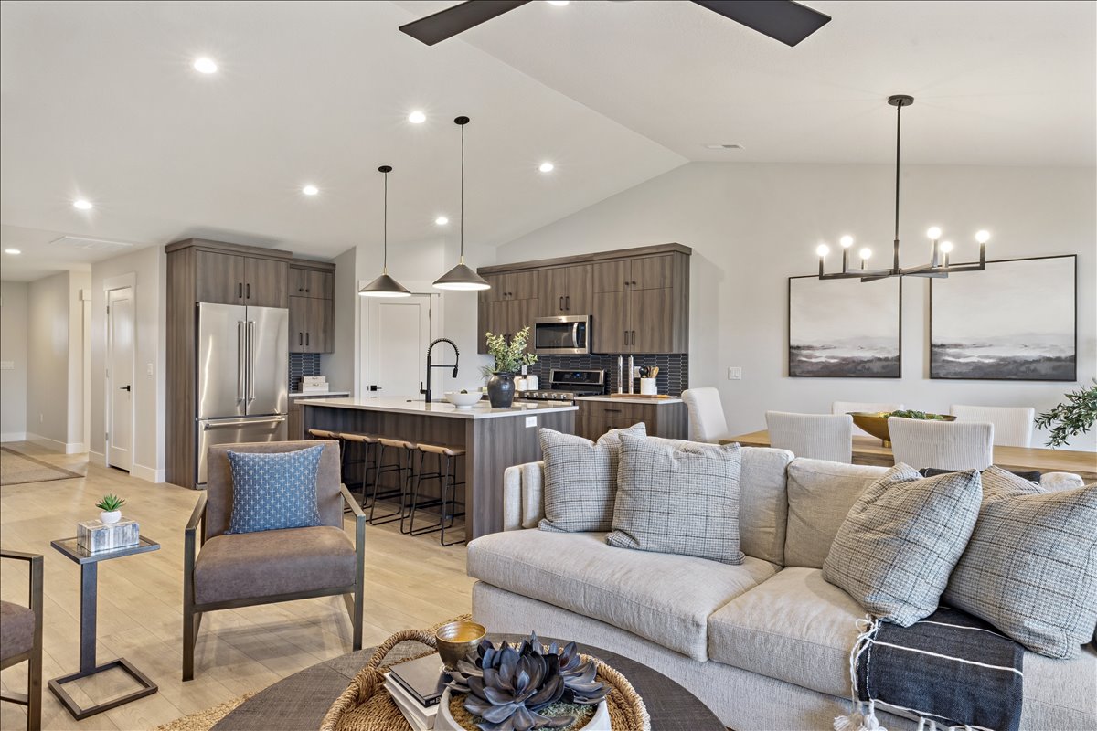 Living area with ceiling fan, hanging lights, light wood-style flooring, and vaulted ceiling