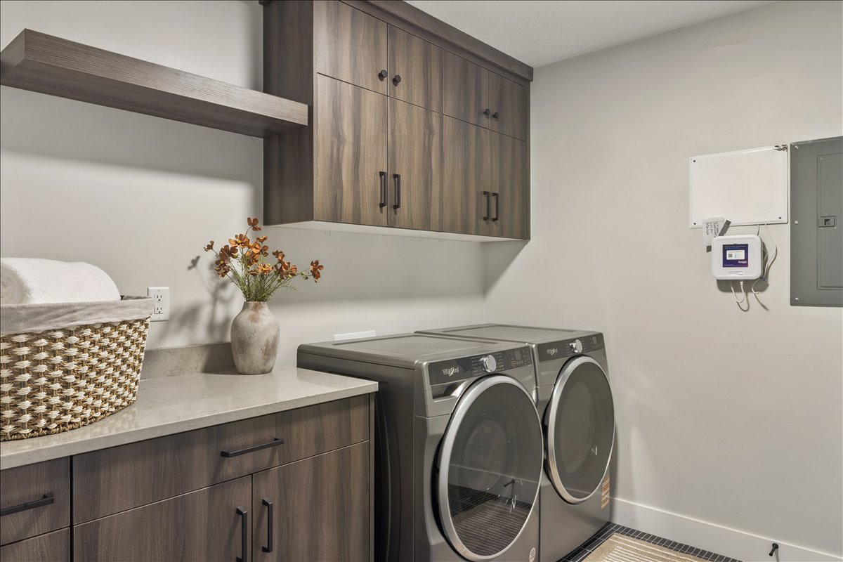 Laundry room featuring electric panel, washer and clothes dryer, and cabinet space