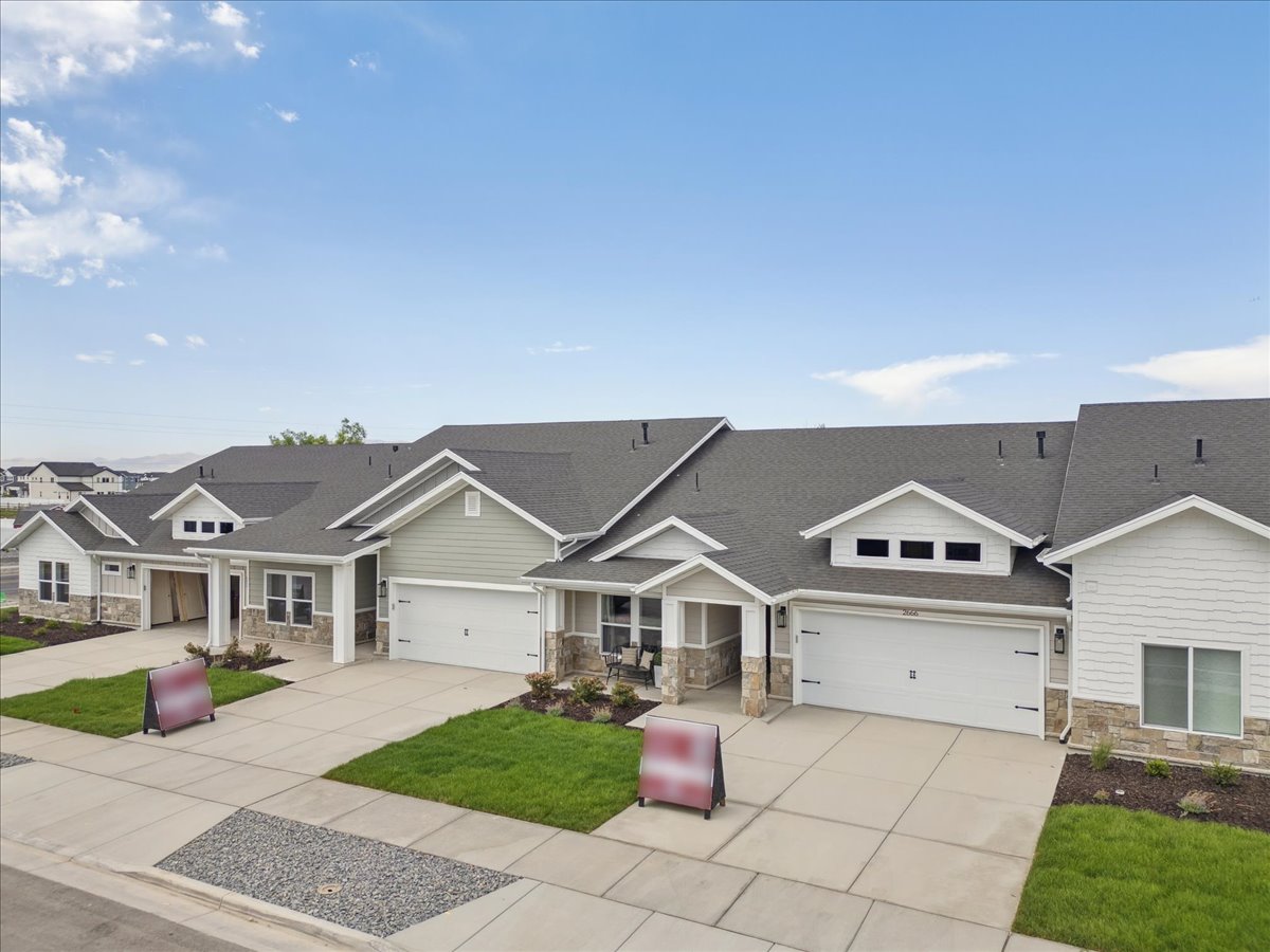 Craftsman-style home with stone siding, driveway, roof with shingles, an HOA front lawn, and covered porch