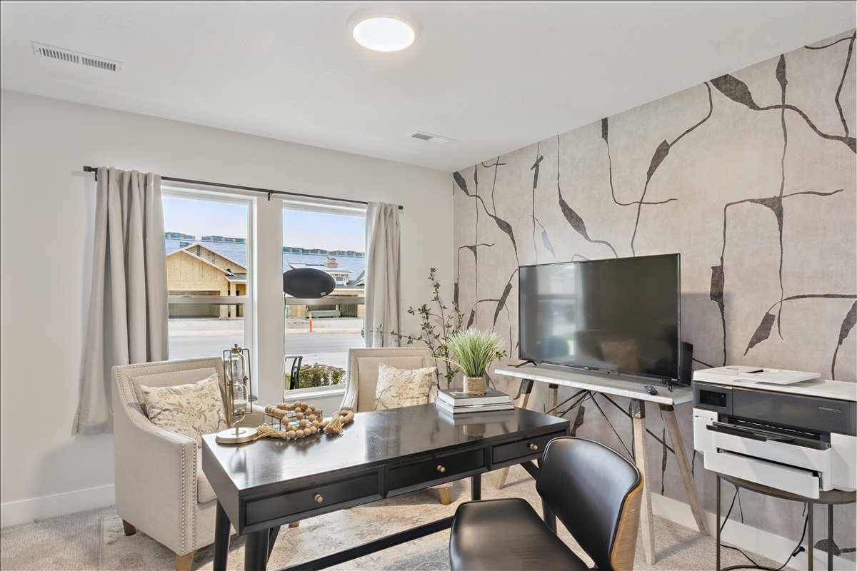 Carpeted home office featuring an accent wall and baseboards