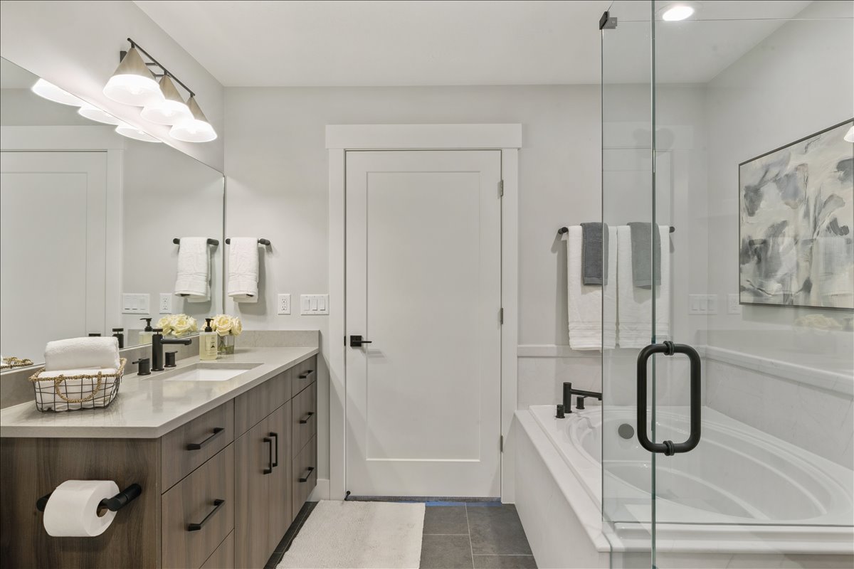 Bathroom with vanity, a shower stall, a garden tub, and dark tile patterned flooring
