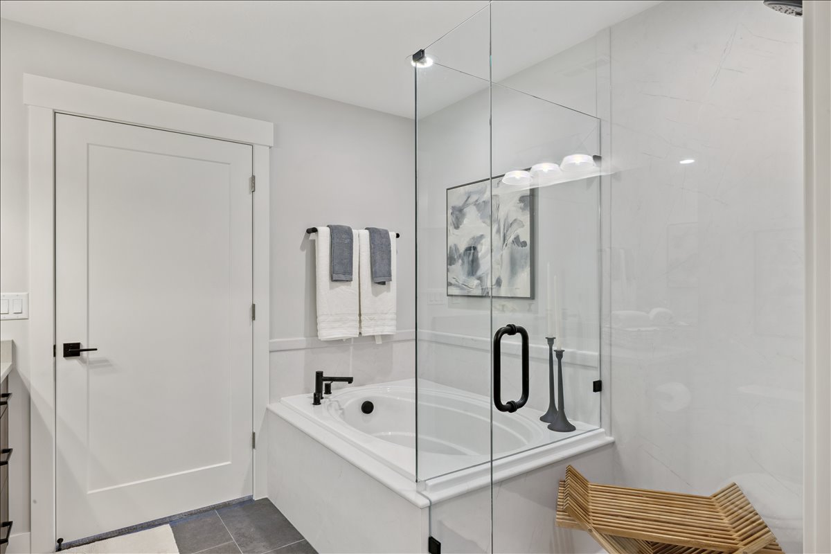 Full bath featuring vanity, a stall shower, a garden tub, and dark tile patterned flooring