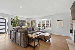 Living room with a fireplace, light wood-style floors, and recessed lighting