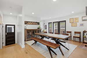 Dining space with french doors, light wood-style flooring, wood walls, and recessed lighting