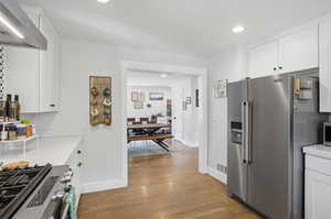 Kitchen with white cabinets, stainless steel appliances, dark wood finished floors, recessed lighting, and light stone countertops