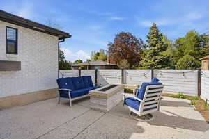 Fenced backyard featuring a patio area and an outdoor living space with a fire pit