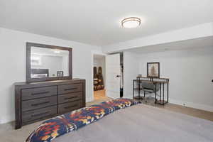 Bedroom featuring light carpet and a desk