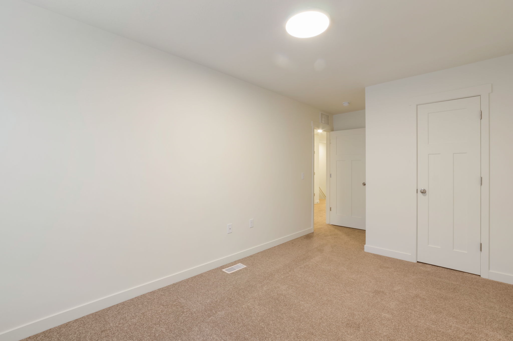 Unfurnished bedroom with light carpet and baseboards