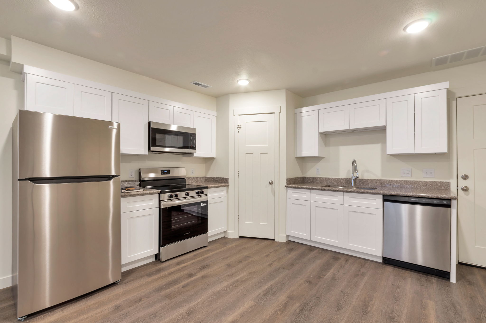 Kitchen with stainless steel appliances, white cabinetry, dark wood-style flooring, dark stone counters, and recessed lighting