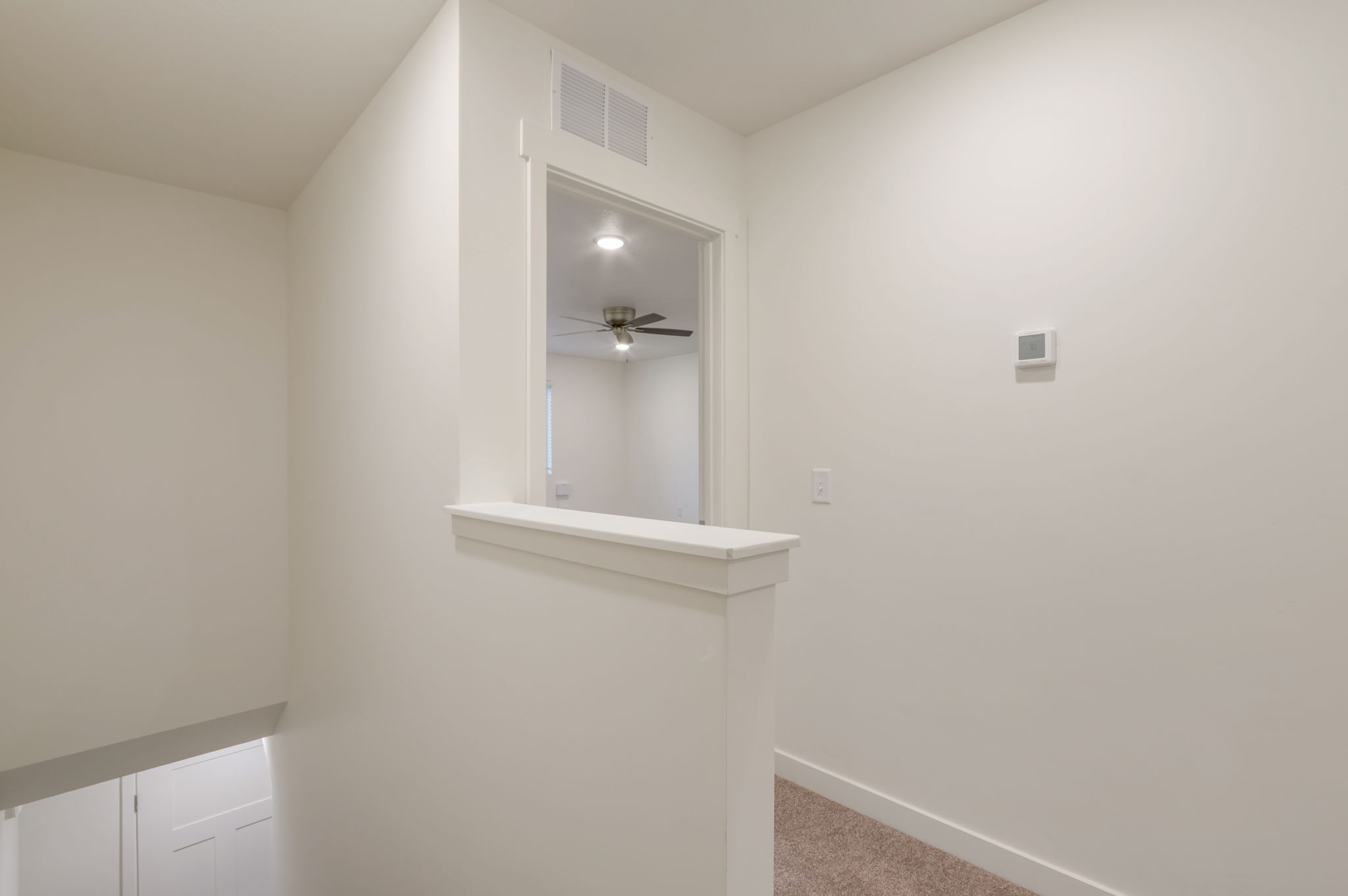 Corridor featuring light colored carpet and baseboards