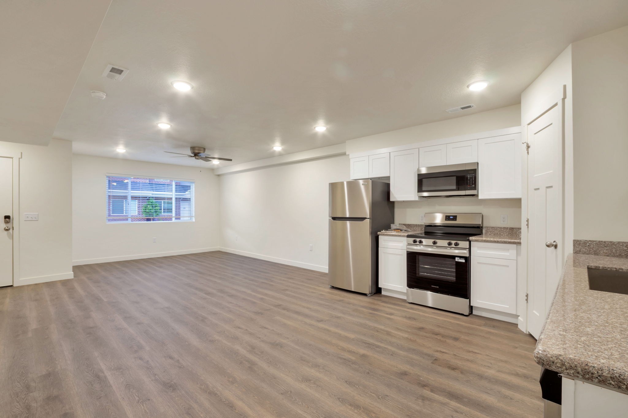 Kitchen with stainless steel appliances, white cabinetry, light stone countertops, light wood-type flooring, and recessed lighting