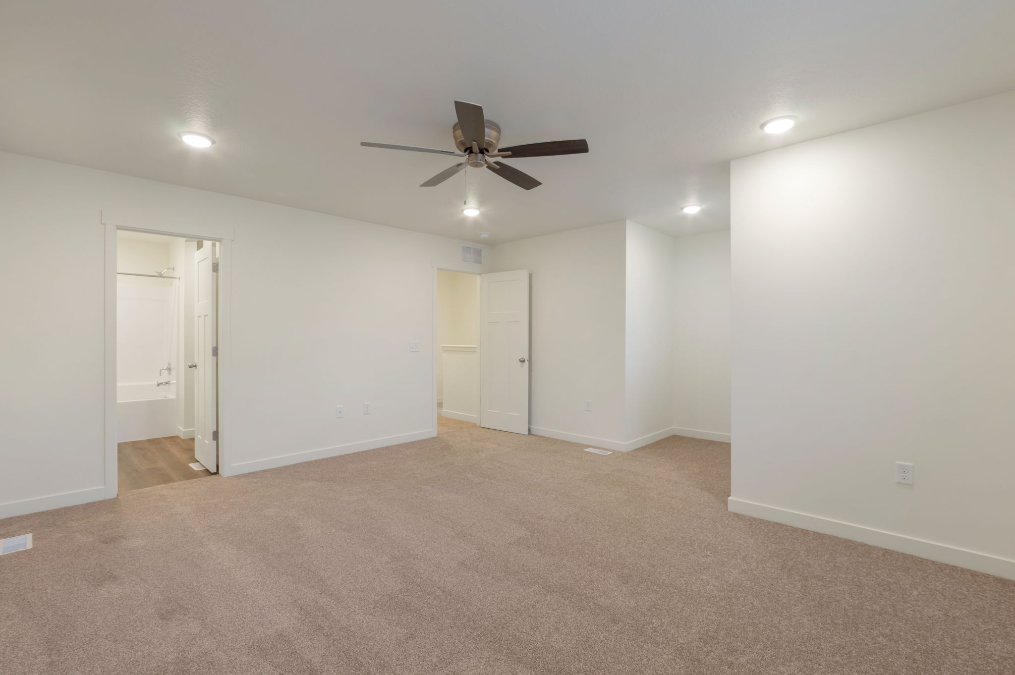Unfurnished bedroom with light carpet, ceiling fan, recessed lighting, and ensuite bath