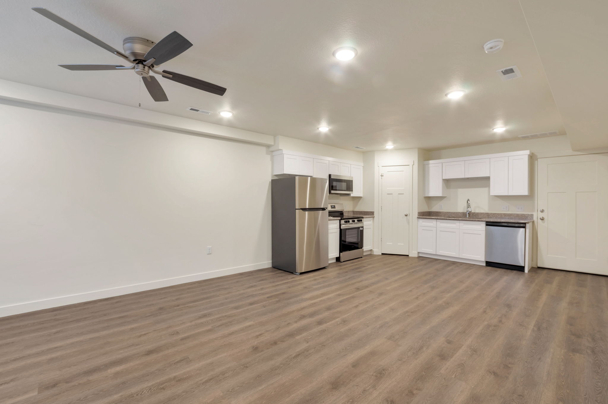 Kitchen featuring stainless steel appliances, white cabinets, dark wood-style floors, a ceiling fan, and recessed lighting