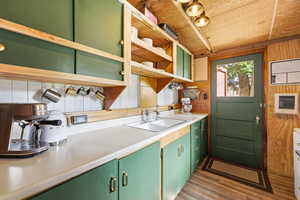Kitchen featuring green cabinetry, light countertops, open shelves, wooden walls, and wooden ceiling