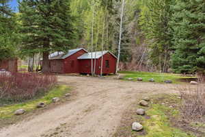 View of property exterior with faux log siding, a lawn, and dirt driveway